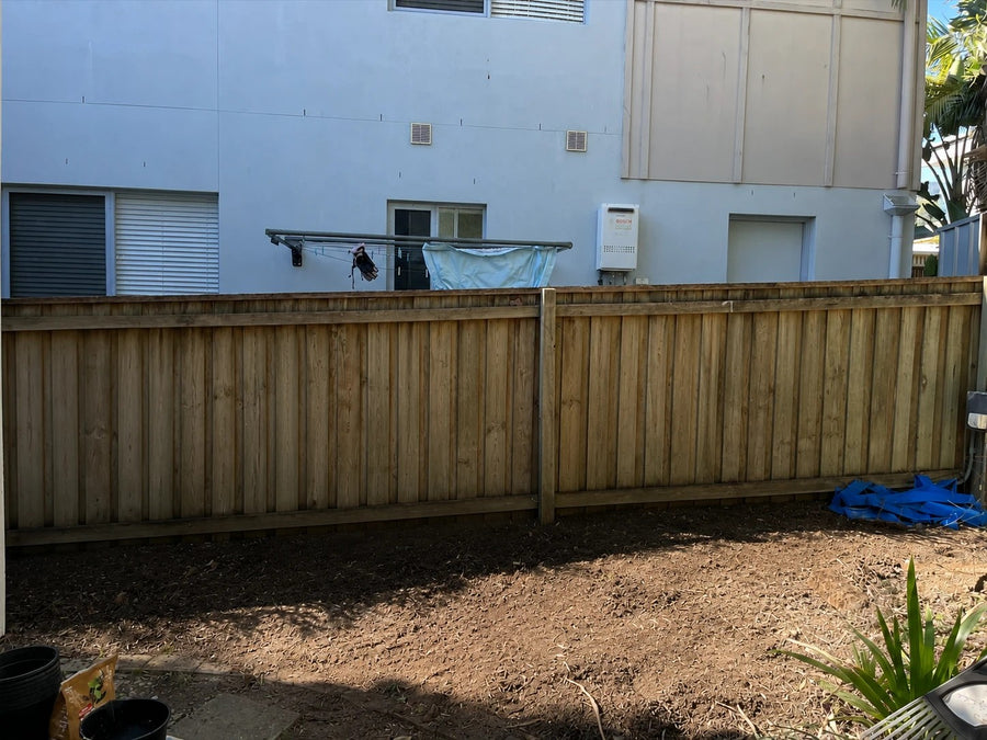 Before: Timber fence with two storey townhouse windows overlooking the yard, screened by an advanced Lilly Pilly hedge