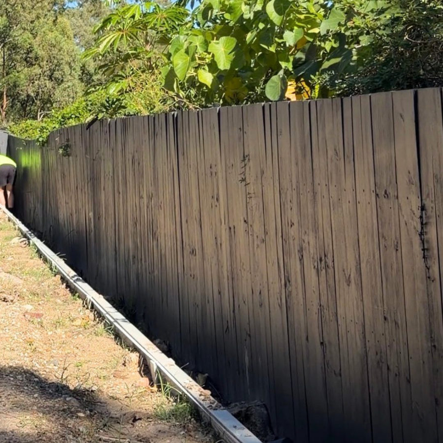 Before: a dark timber fence before and after a dense hedge was planted along it